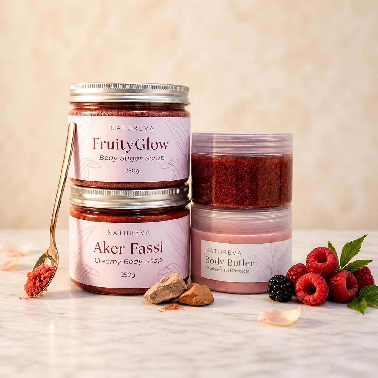 مجموعة عناية بالجسم من ناتشوريفا تضم مقشر FruityGlow وصابونية Aker Fassi وزبدة الجسم مع فواكه وتفاصيل طبيعية على خلفية رخامية.